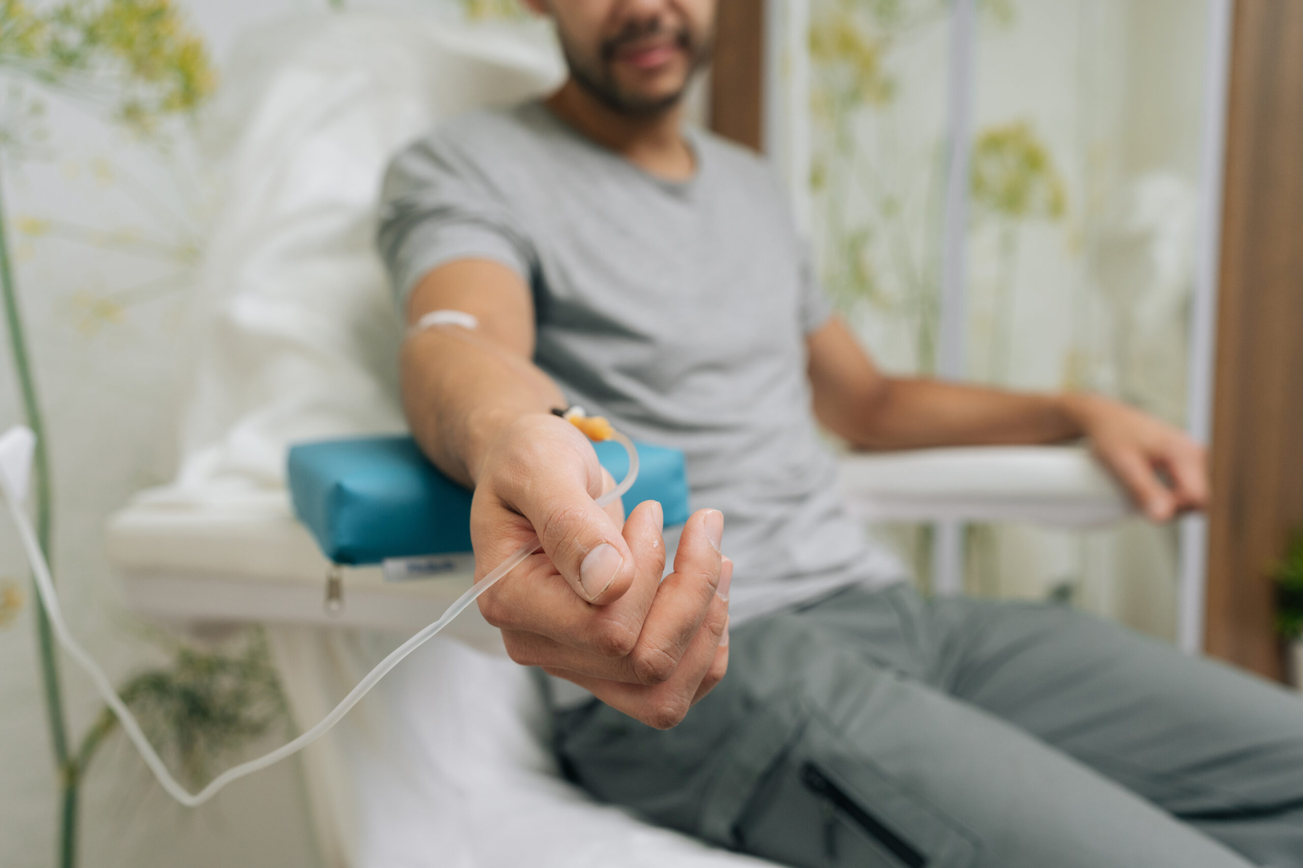 Patient receiving intravenous infusion treatment through iv drip on their arm, focusing on healthcare, medicine, medical therapy, and vitamin benefits in clinic setting.